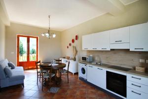 een keuken met witte kasten en een tafel en een eetkamer bij Il giardino al mare di Anna in Caronia Marina