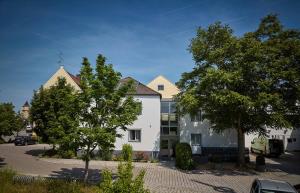 une maison blanche avec des arbres dans un parking dans l'établissement Gästehaus Wenisch, à Straubing