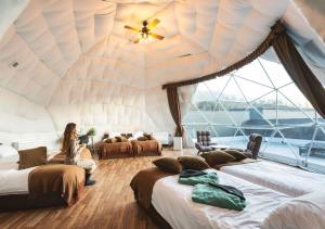 a woman sitting in a room with four beds at VISION GLAMPING Resort & Spa 山中湖 ビジョングランピングリゾート山中湖 in Yamanakako