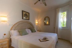 ein Schlafzimmer mit einem großen weißen Bett mit einem Buch darauf in der Unterkunft Oliva Nova Villa Mar in Oliva