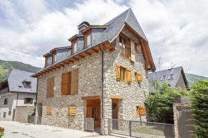 una vieja casa de piedra con techo de gambrel en Luderna - Casa eth Farrow 2 en Vielha