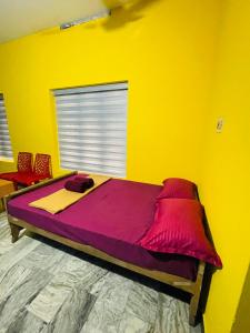 Dormitorio amarillo con cama grande con sábanas moradas en Night Space hostel, en Kalpetta