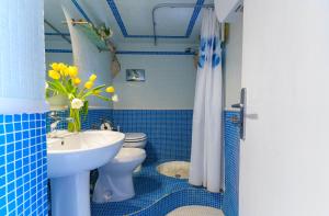 bagno piastrellato blu con lavandino e servizi igienici di Torre di Scopello a Scopello