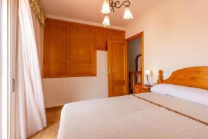 1 dormitorio con cama blanca y armarios de madera en Casa con jardín a pocos pasos del mar, en Denia