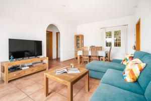 ein Wohnzimmer mit einem blauen Sofa und einem TV in der Unterkunft Villa Isabel in Cala En Porter in Cala en Porter
