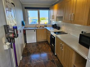 uma cozinha com armários de madeira e piso em azulejo em Mansefield em Lerwick