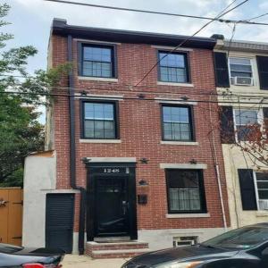 a red brick building with a black door at Fun Fishtown Rowhome - Sleeps 4 in Philadelphia