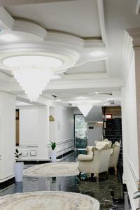 d'un salon avec des chaises et un plafond orné de lustres. dans l'établissement Ko'k Saroy Plaza Hotel, à Samarcande