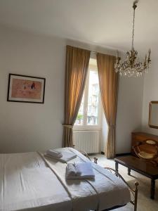 1 dormitorio con cama, lámpara de araña y ventana en Maison Marisa, en La Spezia