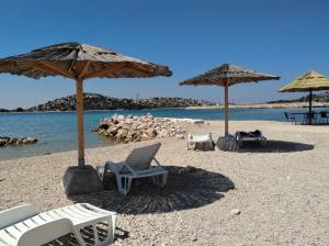 due sedie e ombrelloni su una spiaggia sabbiosa di Tribunia Beach Hotel a Tribunj (Trebocconi)