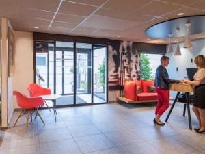 a man and a woman standing in a lobby at ibis Tours Nord in Tours