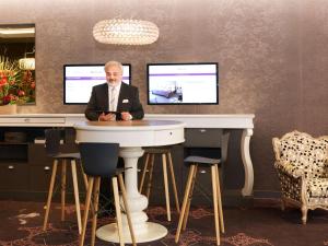 a man sitting at a table with two monitors at Mercure Toulouse Centre Wilson Capitole in Toulouse
