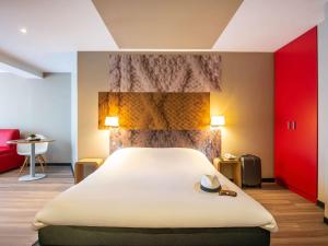 a bedroom with a large bed with a hat on it at ibis Nuits Saint Georges in Nuits-Saint-Georges