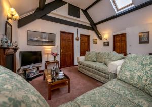 uma sala de estar com dois sofás e uma televisão em The Cottage em Llanbedrog