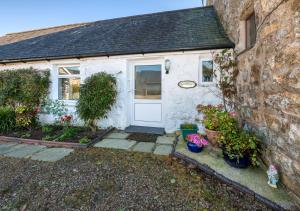 um chalé branco com uma porta e algumas plantas em The Cottage em Llanbedrog