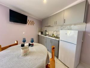 eine Küche mit einem Tisch und einem weißen Kühlschrank in der Unterkunft Anemos Studios & Apartments in Póros