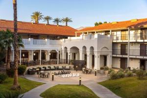un patio de un edificio con mesas y sillas en Embassy Suites by Hilton Palm Desert en Palm Desert