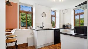 a kitchen with white cabinets and a clock on the wall at Tranquil countryside cottage for two in Wrexham