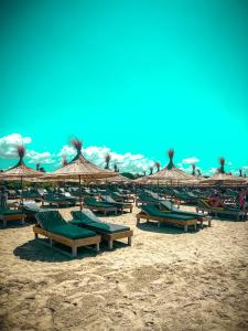 a group of beach chairs and umbrellas on a beach at Aromë natyre by AlaraFarm in Durrës