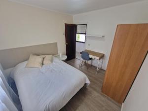 a bedroom with a white bed and a desk at Praia Santa Baia in Vigo