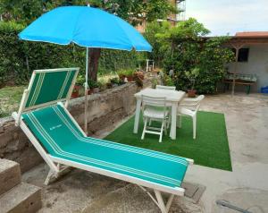 una sombrilla azul y una mesa y sillas en el césped en Casa Travaglini en Fano