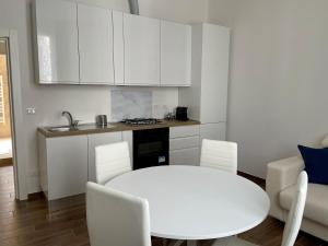 a white kitchen with a white table and chairs at Casa Curcio in Bologna