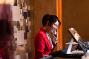 a woman talking on a phone in front of a laptop at Kempinski The One Suites Hotel Shanghai Downtown in Shanghai