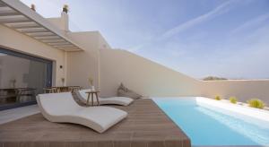 a villa with a swimming pool and white furniture at Pnoe Luxury Suites in Fira