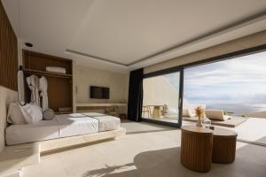 a bedroom with a bed and a large window at Pnoe Luxury Suites in Fira