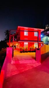 una casa roja con luces rosas delante en Night Space hostel en Kalpetta