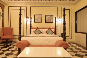 a bedroom with a bed and a table and a chair at Kesarbagh Palace in Chittaurgarh