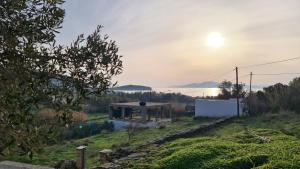 a house on a hill with the sunset in the background at Aegean Sunset in Agios Sostis