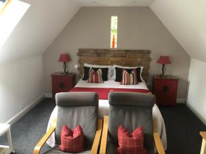 a attic bedroom with a bed and two chairs at The Steppes Holiday Cottages in Hereford