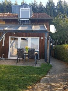 una mesa y sillas frente a una casa en Gemütliches Ferienhaus mit Kamin und eigenem Garten in bayerischem Feriendorf, en Zandt