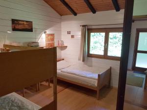 a room with a bed and a desk and windows at Gemuetliches Blockhaus in Steinberg