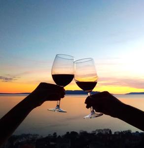 dwoje ludzi trzymających kieliszki do wina przed zachodem słońca w obiekcie Apartment with view in Rijeka w mieście Rijeka