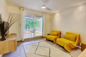 Saint-PaulにあるLe petit Lux du Lagon - La Saline les Bainsのリビングルーム(黄色い椅子2脚、窓付)