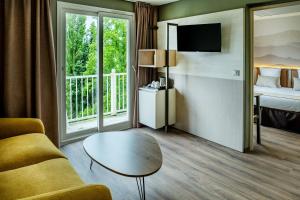 Habitación de hotel con sofá, mesa y cama en Hôtel La Solitude, en Lourdes