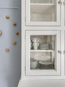 a white cabinet with plates and dishes in it at Alte Fischfabrik Lauterbach "MehrZeit am Bodden" in Lauterbach