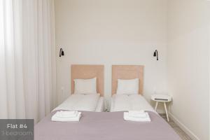 duas camas num quarto branco com toalhas em Dandelion Apartments Stabu em Riga