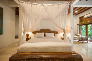 a bedroom with a canopy bed in a room at The Lavana Ziza Living And Villas Seminyak in Kerobokan +42 photos