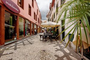 una calle vacía con mesas y sombrillas en una ciudad en Família Dória Nóbrega T0, en Funchal