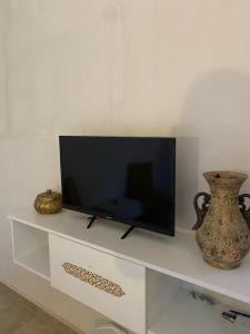 una TV a schermo piatto seduta su una mensola bianca di Djerba rêve vacances Zohra a Midoun
