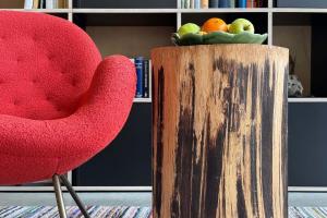 a red chair and a bowl of fruit on a wooden stand at Urlaub in Designer-Ferienwohnung, die zusätzlich mit traditionellem Weinkeller und hochwertiger Einrichtung überzeugt in Sausal