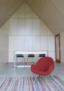 a red chair in a room with a table and chairs at Urlaub in Designer-Ferienwohnung, die zusätzlich mit traditionellem Weinkeller und hochwertiger Einrichtung überzeugt in Sausal