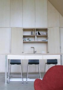 a kitchen with a sink and two stools at Urlaub in Designer-Ferienwohnung, die zusätzlich mit traditionellem Weinkeller und hochwertiger Einrichtung überzeugt in Sausal