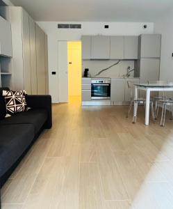 studio 3 - milano في ميلانو: غرفة معيشة مع أريكة سوداء ومطبخ