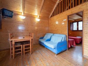 Habitación con silla azul, mesa y TV. en Centro de Vacaciones Morillo de Tou - Ainsa en Aínsa