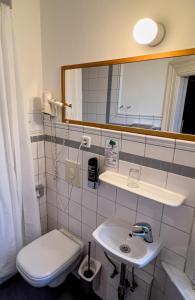 ein Badezimmer mit einem Waschbecken, einem WC und einem Spiegel in der Unterkunft Hotel-Maison Am Olivaer Platz in Berlin