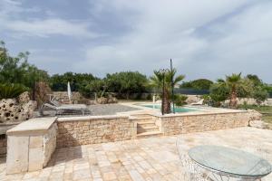 a patio with a stone wall and a table at Trulli San Pietro in Putignano
